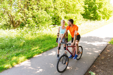 Obraz premium happy couple with rollerblades and bicycle riding