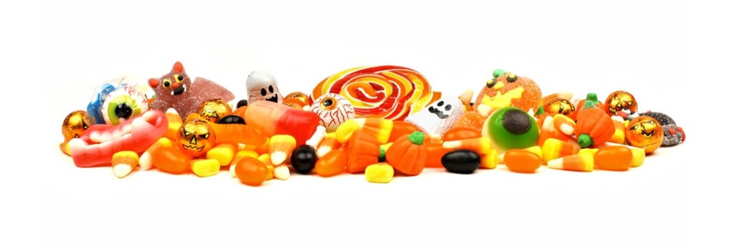 Long pile of colorful Halloween candy and sweets over a white background