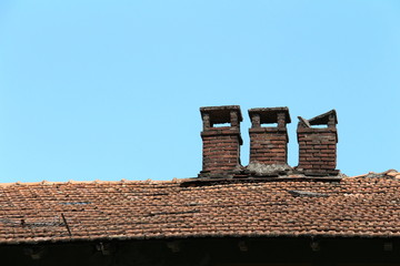 Naklejka premium Brick chimney on tile roof of an old wooden house