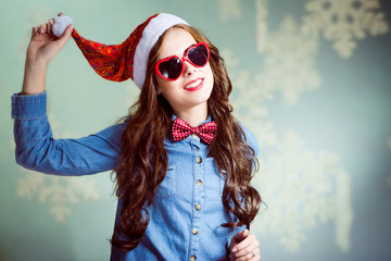 Funny brunette girl in Christmas hat and heart-shaped glasses