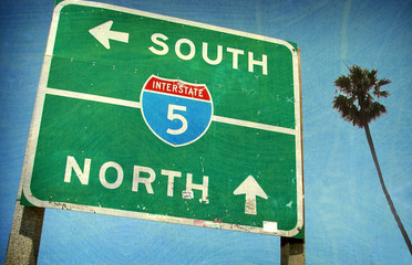 aged and worn vintage photo of california interstate freeway sign and palm tree - Powered by Adobe