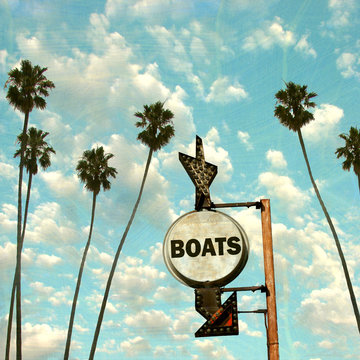 aged and worn vintage photo of boat sign with palm trees