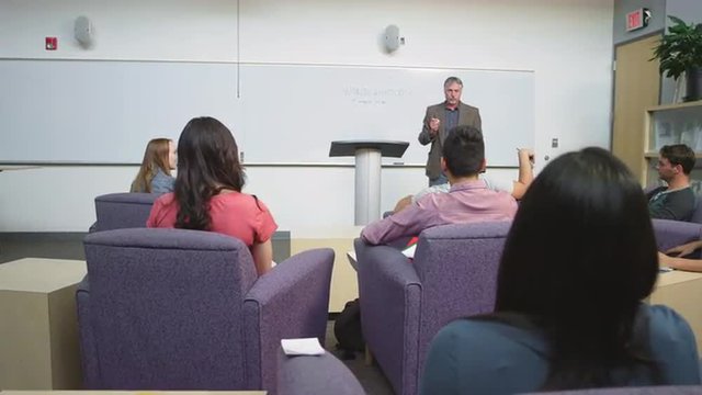 A student raises her hand and the professor calls on other people
