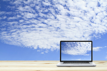 Laptop computer on wooden floor with sky  background.