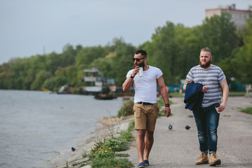 Fototapeta premium Two men walk and drink coffee