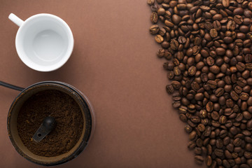 Cup of coffee, coffee grinder and beans on brown background. Top