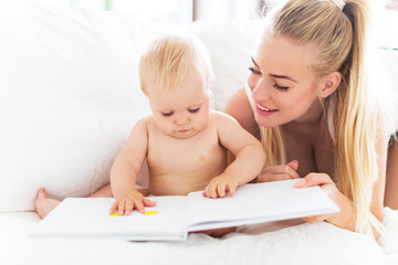 Obraz na płótnie Canvas Mother reading book with baby