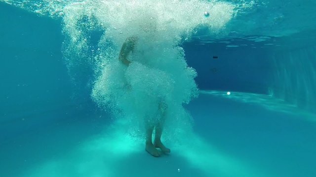 Teenager girl jumping the swimming pool. Underwater footage.
