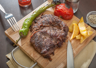 Grilled beef steak served with grilled tomatoes, peppers and chips