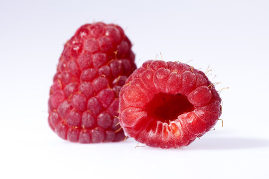two red raspberries isolated on white background