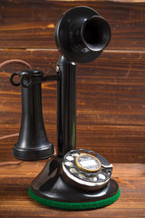 Vintage, antique candlestick telephone with dial on wood backgro