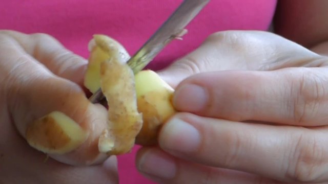 Female hands closeup. Knife peeling potatoes