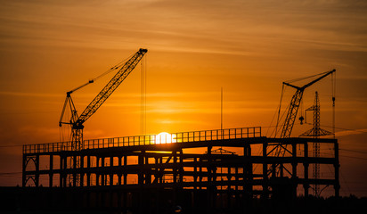 cranes and buildings under construction against the setting sun