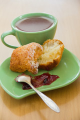 In the green bowl of fresh homemade muffin with jam and a cup of black tea