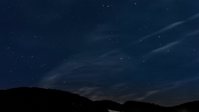 stars moving in night sky over mountain ridge