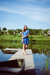 Fototapeta na wymiar Relaxing brunette young pretty girl in blue dress on bridge