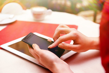 Woman with mobile phone and tablet computer in cafe shop