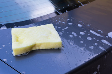 Motor hood being cleaned with sponge and soap