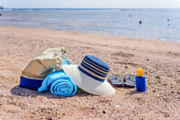 Beach Bag and Sun Hat on Sunny Deserted Beach