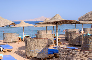 Thatched beach umbrellas and recliner chairs