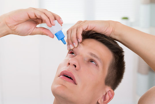 Man Pouring Medicine Drops In His Eyes