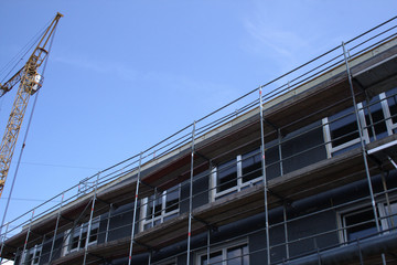 Fototapeta premium Yellow erection crane next to a shell construction, constrution industry, real estate