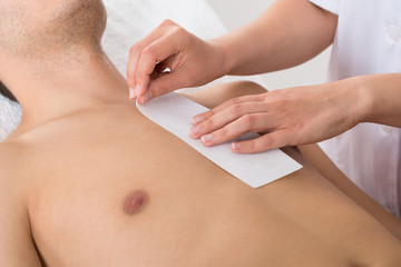 Person Hands Waxing Man's Chest