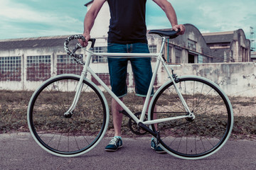 Naklejka premium Young man with a fixie bike. Decadent industrial setting