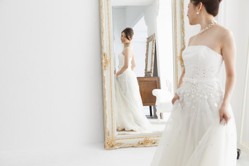 Bride wearing a wedding dress looking at the mirror