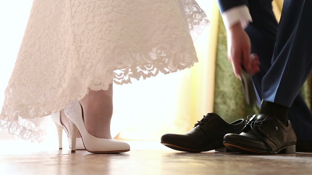 The bride and groom both wear wedding shoes
