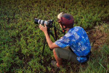 photographer squats makes photos among lakes