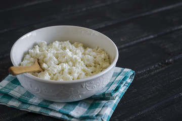 cottage cheese in a white bowl on a dark wooden background