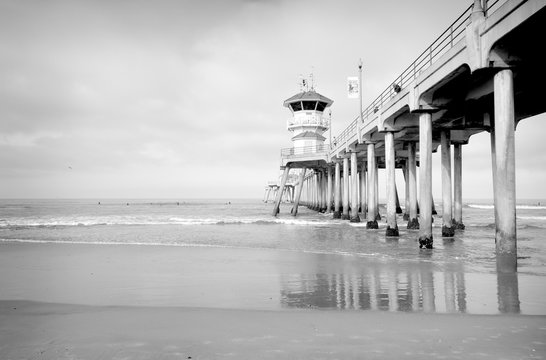 black and white photo of ocean pier with small waves