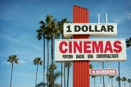 aged and worn vintage photo of cheap dollar cinemas sign with palm trees