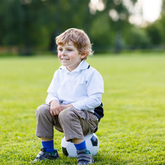 Fototapeta premium Blond boy of 4 resting with football on football field