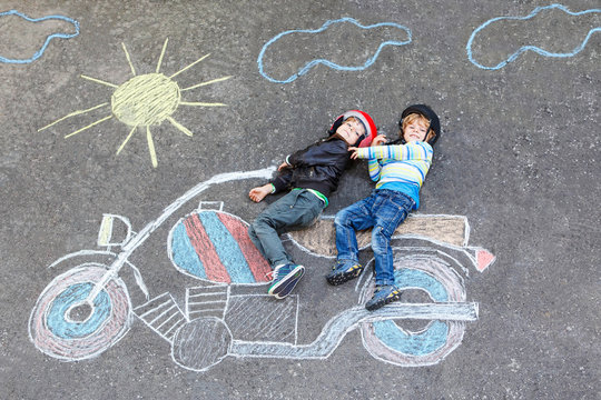 Two kid boys in helmet with motorcycle picture drawing with colo