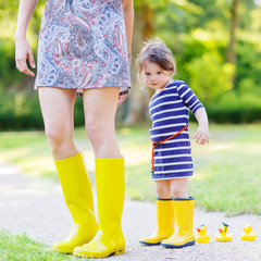 Mother and little adorable child in yellow rubber boots