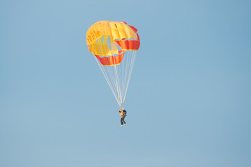 Parachutist in bright yellow-orange parachute parachute