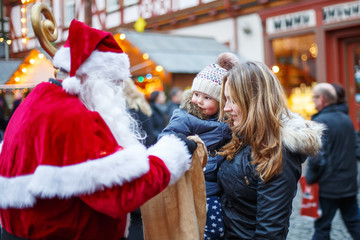 Little toddler girl with mother on Christmas market.