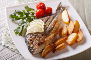 dorado fish with fried potatoes and lemon closeup. horizontal
