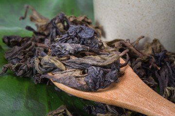 Dry tea leaves and wooden spoon