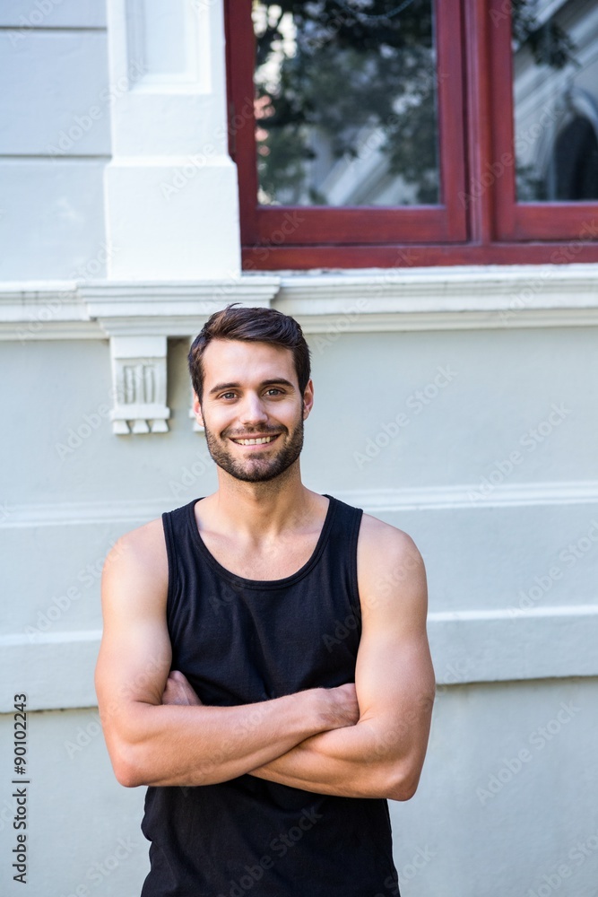 Poster smiling handsome athlete in front of a building