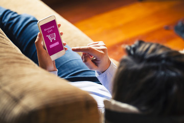 Woman shopping by mobile phone laying at home. Pink screen.