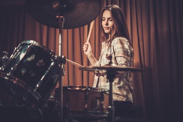 Young cheerful girl behind drums on a rehearsal
