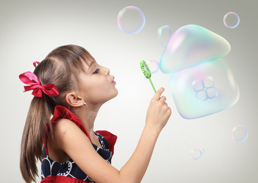 Portrait of Child girl blowing soap bubble forming house, habita
