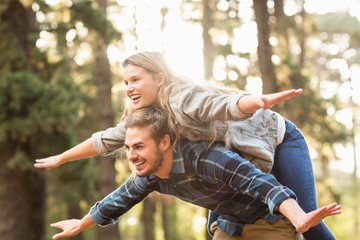 Smiling handsome man giving piggy back to his girlfriend