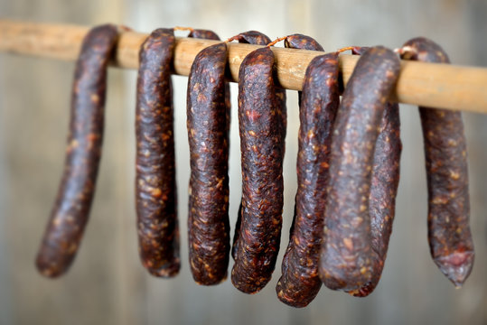 Dunkel ger&auml;ucherte S&uuml;dtiroler Kaminwurzen zur Trocknung aufgeh&auml;ngt