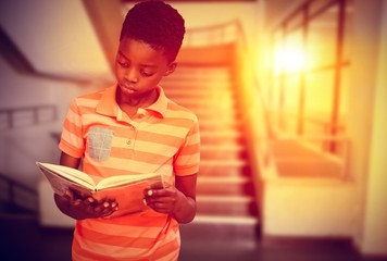Composite image of cute boy reading book in library