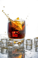 Ice cube droped in cola glass and cola splashing