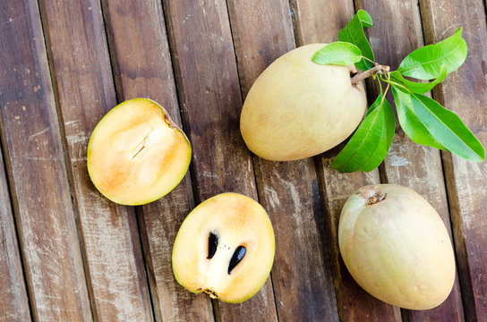 Fresh sweet sapodilla fruit with leaves on wooden background